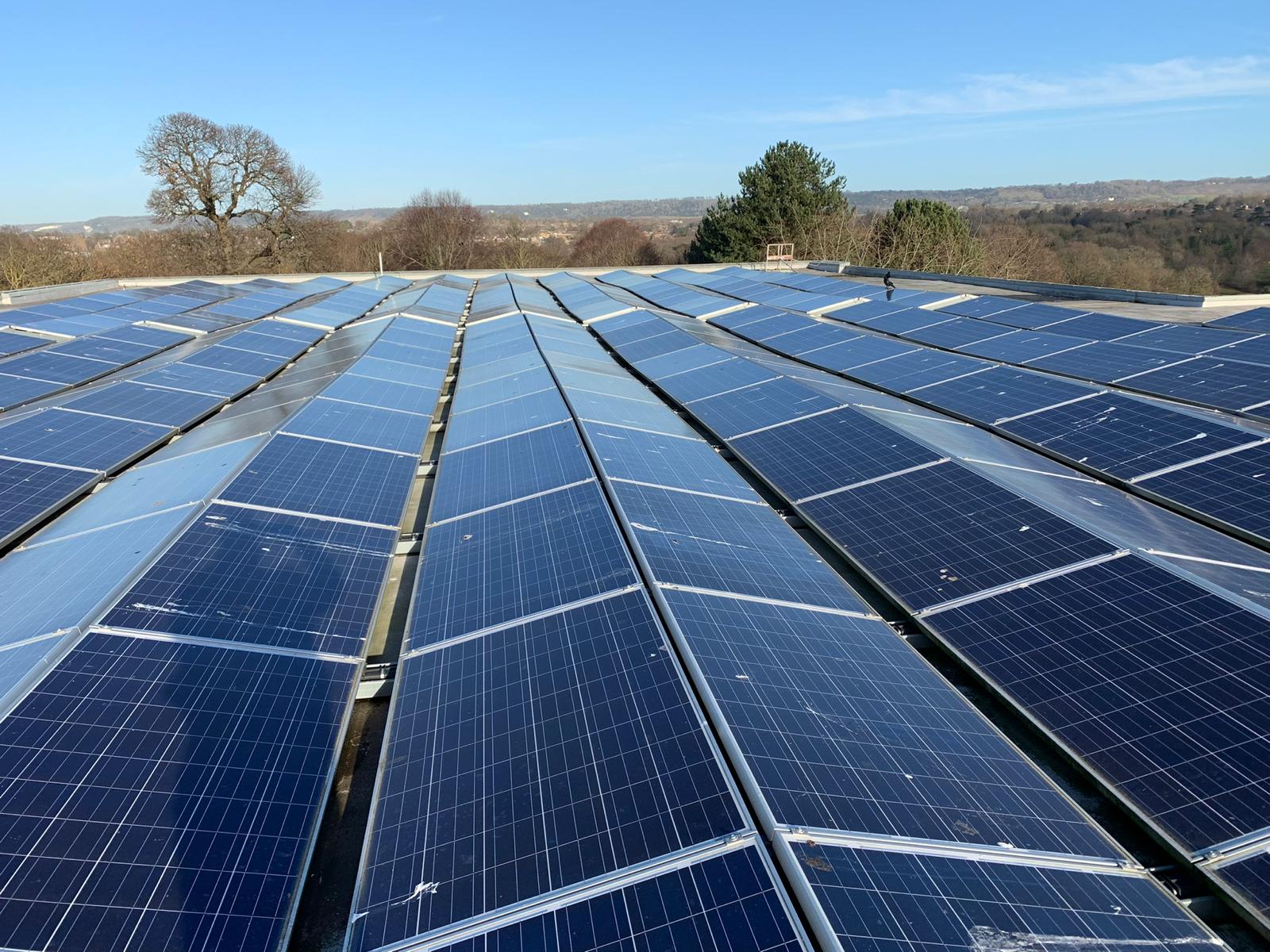 Rows of solar panels installed across a large commercial rooftop